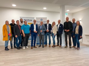 13 Personen posieren vor zwei Roll-ups im Zuge des Events „Flensburg digitalisiert“ 2022.